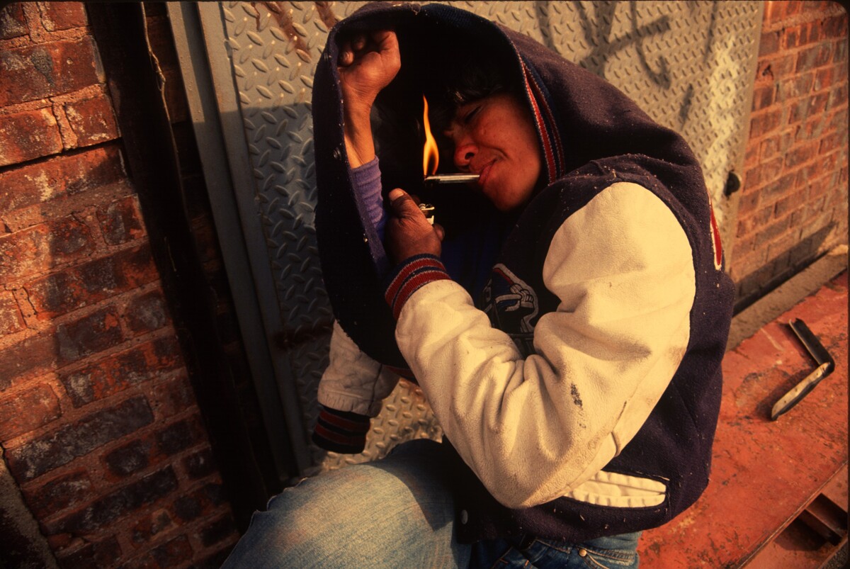 Epidemie cracku zasáhla převážně černošské městské komunity a byla často vykreslována jako drogový problém „jiných“ lidí, před kterým privilegovaní lidé zavírali oči. Ulice Troutman, na které je fotka pořízená, byla v roce 1991 otevřeným tržištěm s drogami a prostitucí, kde si oblouznění často šlehali heroin nebo kouřili crack. Čtvrť, která kopíruje trasu vlaku L, prošla desetiletím gentrifikace.