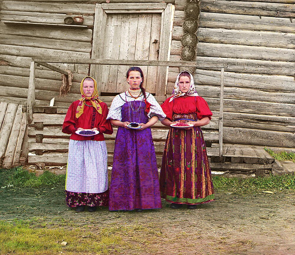 Tři mladé ženy nabízí bobule svým návštěvníkům ve venkovské oblasti podél řeky Šeksny nedaleko města Kirillov. Rok 1909.