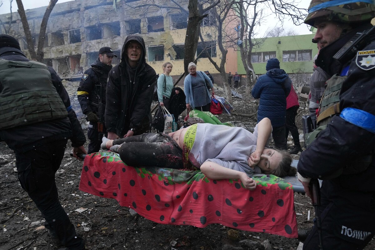 Ukrajinští záchranáři a dobrovolníci nesou zraněnou těhotnou ženu po ostřelování budovy porodnice v Mariupolu, ke kterému došlo v březnu. Příběh bohužel neměl šťastný konec. O život přišla žena i její dítě.