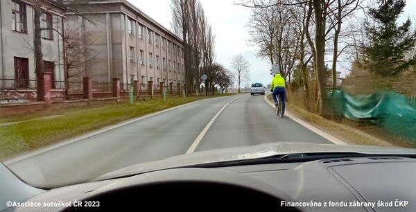 Smí ve vyobrazené dopravní situaci řidič motocyklu s postranním vozíkem přejíždět podélnou čáru souvislou při předjíždění cyklisty? 