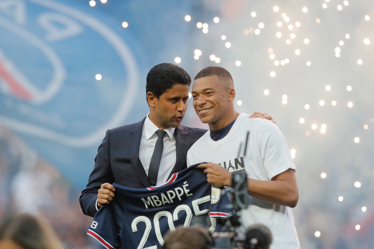 Francúzsky futbalista Kylian Mbappé (vpravo) z Paríža St. Germain drží dres s číslom 2025 oznamujúcim podpis novej trojročnej zmluvy pred zápasom 38. kola francúzskej Ligue 1 Paríž St. Germain – FC Metz v Paríži v sobotu 21. mája 2022. Vľavo stojí prezident futbalového klubu Paríž St. Germain Násir Al-Chelajfí.