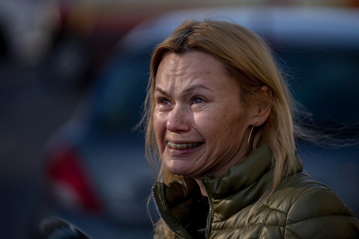 Na snímku žena pláče, když se dívá na zničený bytový dům po raketovém útoku 26. února 2022 v Kyjevě.