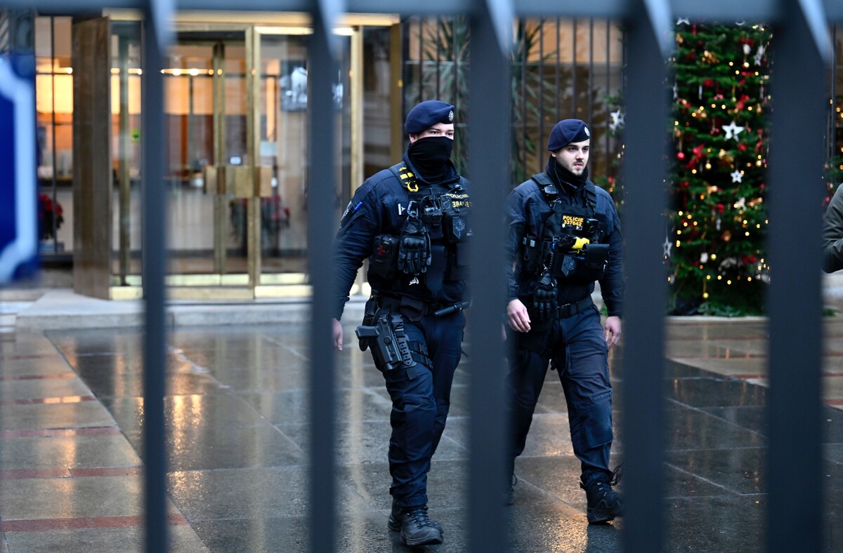 Policajti kráčajú pred budovou Filozofickej fakulty Univerzity Karlovej. 