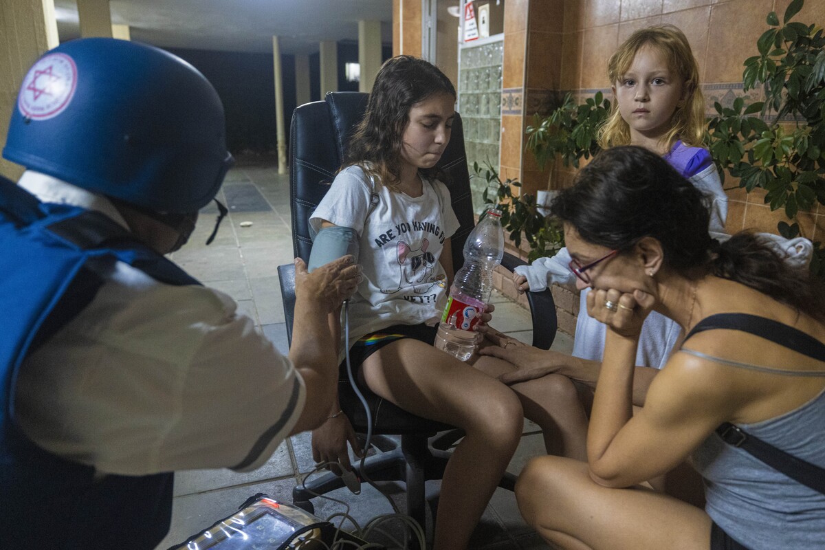 Izraelský zdravotník kontroluje krvný tlak dievčaťa v obytnej budove po zásahu raketou vystrelenej z Pásma Gazy v meste Aškelon na juhu Izraela.
