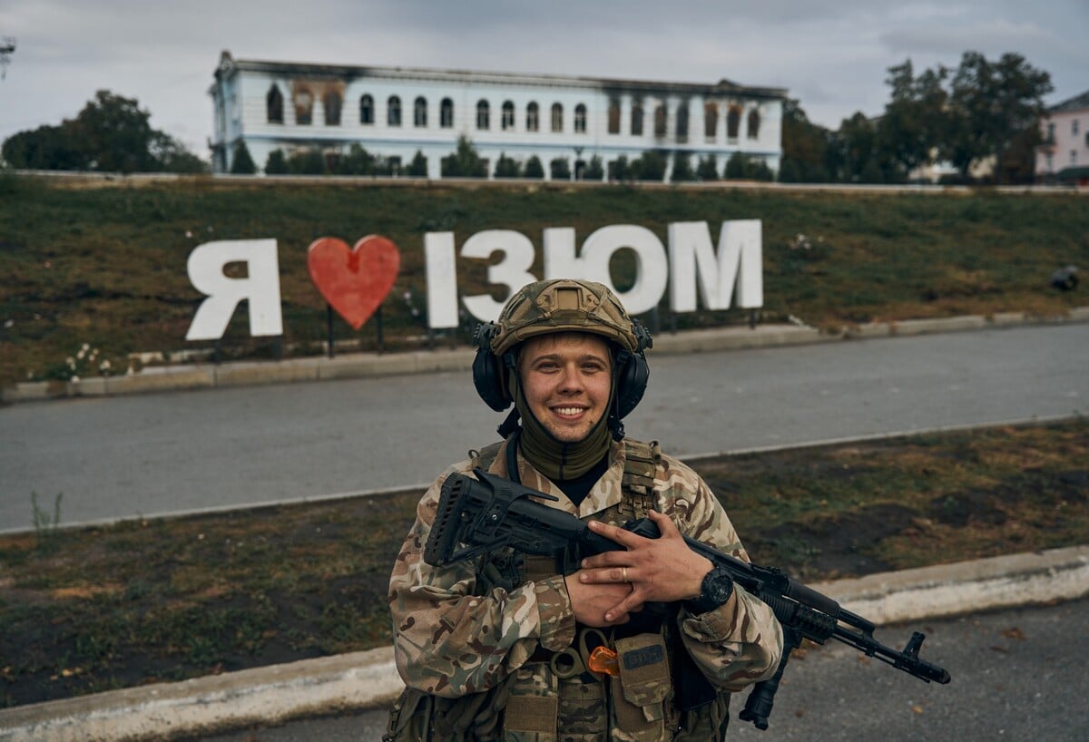 Ukrajinský vojak sa usmieva pred nápisom Milujem Izium v ukrajinskom meste Izium v Charkovskej oblasti. (13. september 2022)