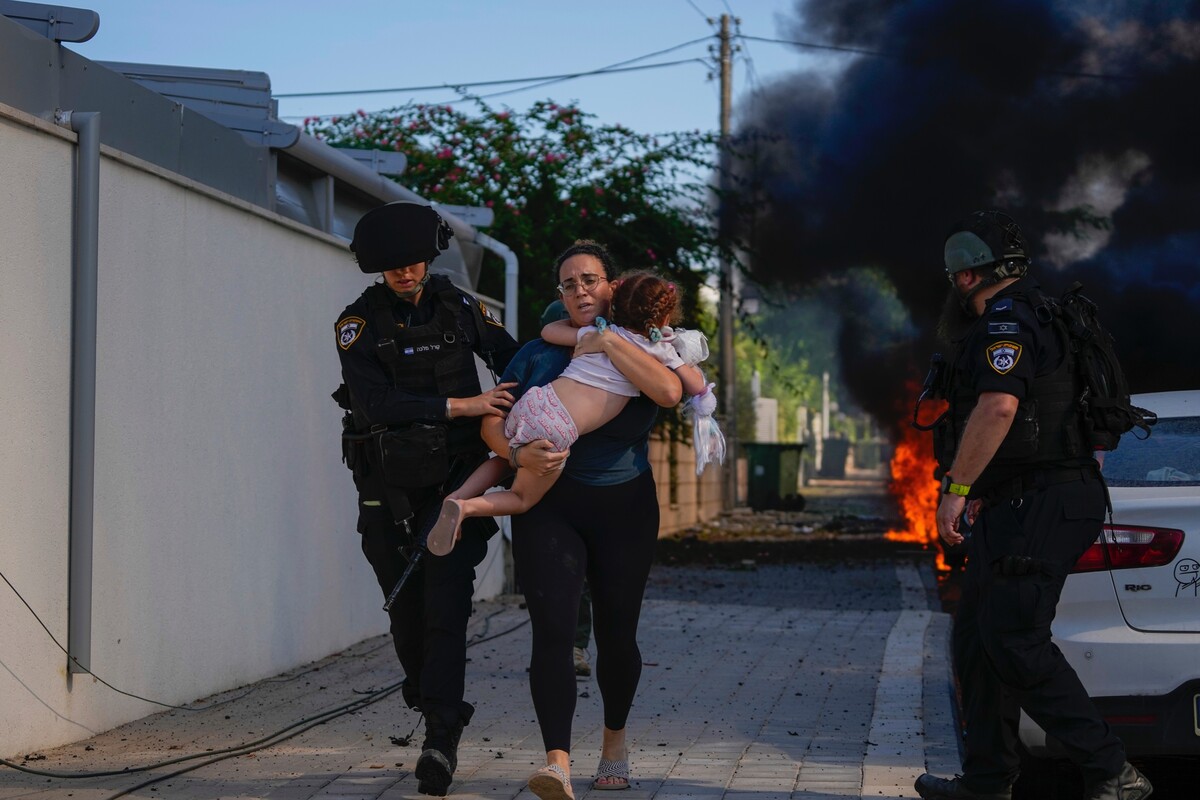 Izraelští policisté evakuují ženu s dítětem v místě dopadu rakety vystřelené z Pásma Gazy.
