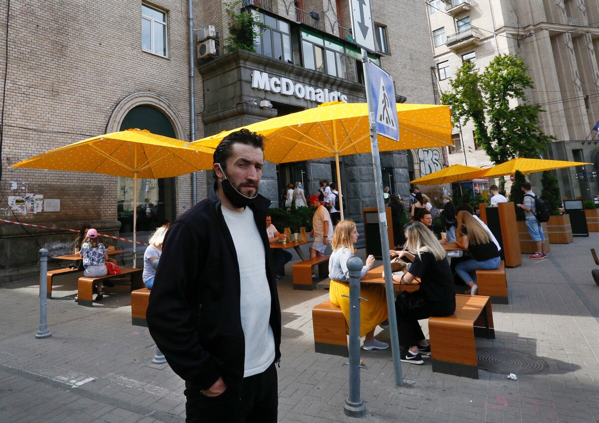 Na archívnej snímke z 9. júna 2020 ľudia, z ktorých niektorí nosia ochranné rúška proti ochoreniu koronavírusu, jedia v exteriéri pred reštauráciou McDonald's v Kyjeve.