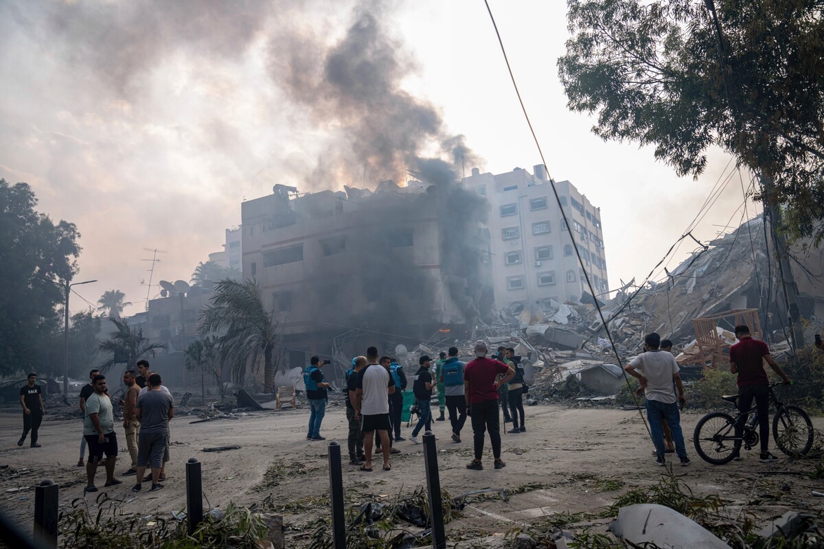 Palestinci zkoumají trosky budovy zasažené izraelským raketovým útokem na Pásmo Gazy.