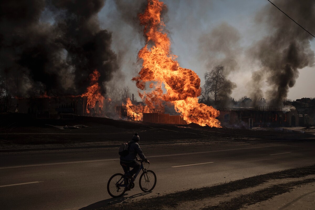 Cyklista prechádza okolo požiaru a dymu po ruskom útoku v Charkove na Ukrajine. Už je to viac ako mesiac, odkedy armáda Vladimira Putina odštartovala špeciálnu vojenskú operáciu. (25. marca 2022)