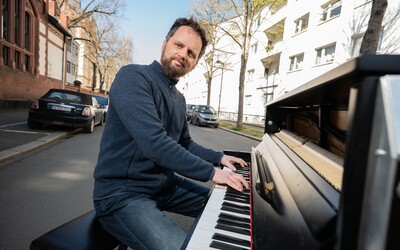 Hudebník vytáhl klavír ven a hraje pro své sousedy uprostřed ulice. I takto vypadá koronavirová krize.