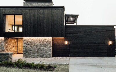 Černý dřevěný obklad v kombinaci s kamenem na fasádě jako kontrast k modernímu interiéru, který obývá mladá rodina
