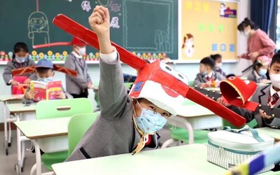 Čínští školáci se vrátili do škol v kloboucích s metrovými tyčemi na hlavách, aby se nepřibližovali jeden k druhému