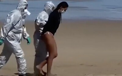 Muži ve skafandrech na španělské pláži zatkli ženu s koronavirem, která namísto izolace surfovala