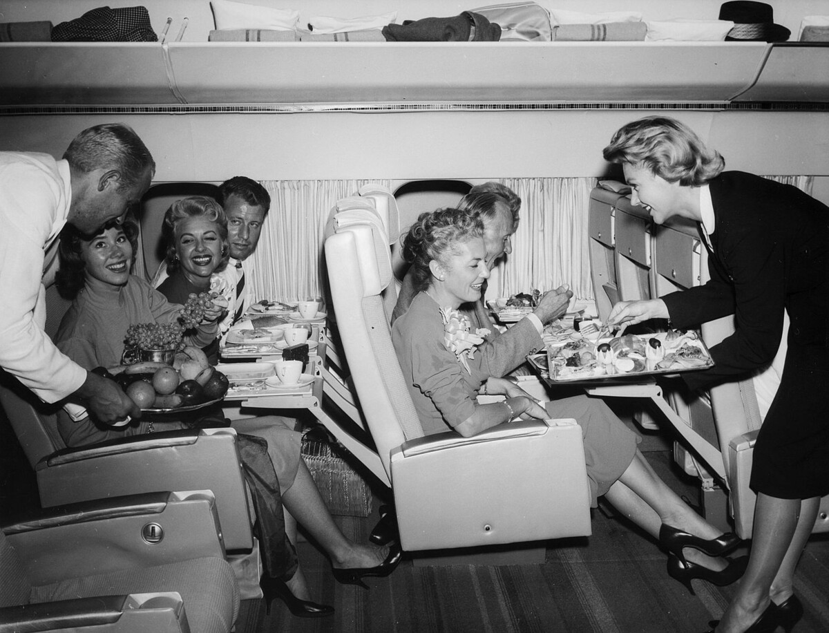 Pasažieri v lietadle spoločnosti SAS (Scandinavian Airlines). V zlatej ére lietania nosili pasažieri luxusné šaty a na palube ich čakalo výborné jedlo.