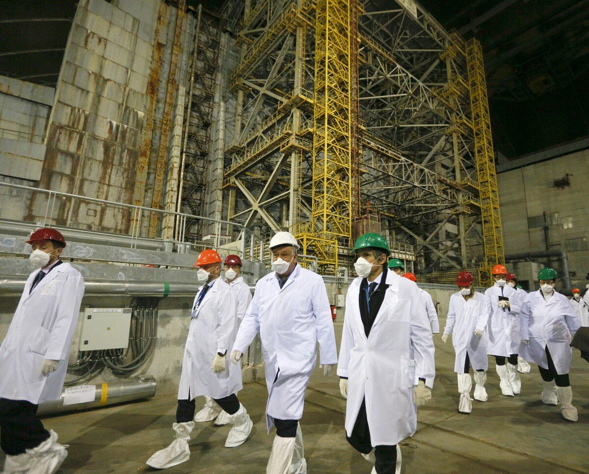 Riaditeľ Medzinárodnej agentúry pre atómovú energiu (MAAE) Mariano Grossi (uprostred vpravo) so zamestnancami neďaleko krytu reaktora jadrovej elektrárne v ukrajinskom meste Černobyľ 27. apríla 2021.