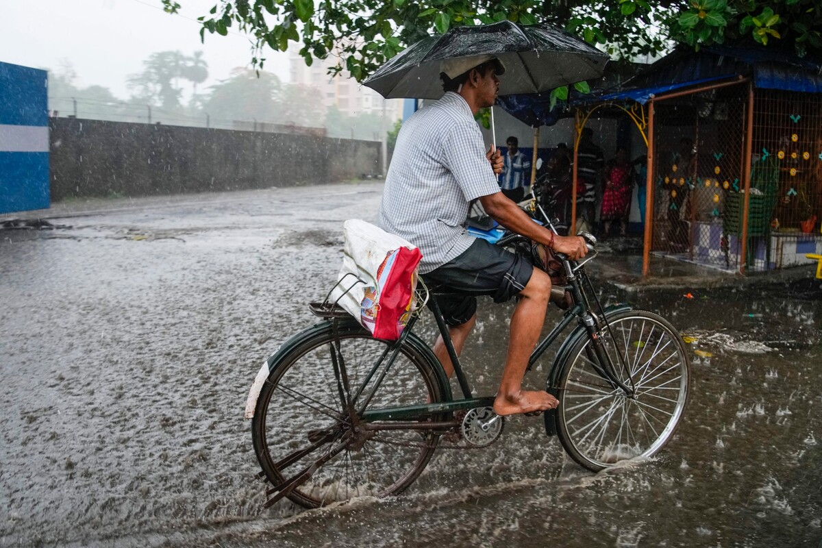 Muž jede v Kalkatě na kole zaplavenou ulicí. Foceno 10. května 2022.