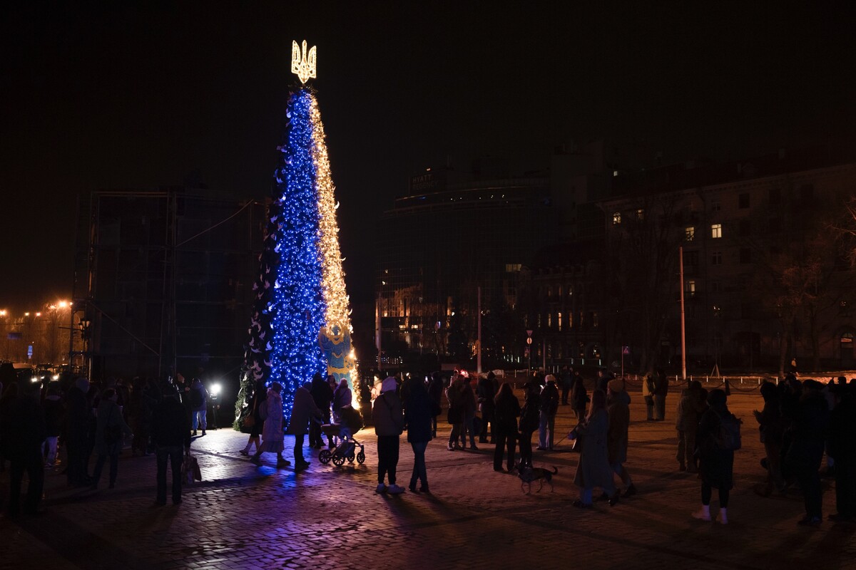 Ľudia sa zhromažďujú okolo vianočného stromčeka vo farbách ukrajinskej vlajky 23. decembra 2022 v Kyjeve. 