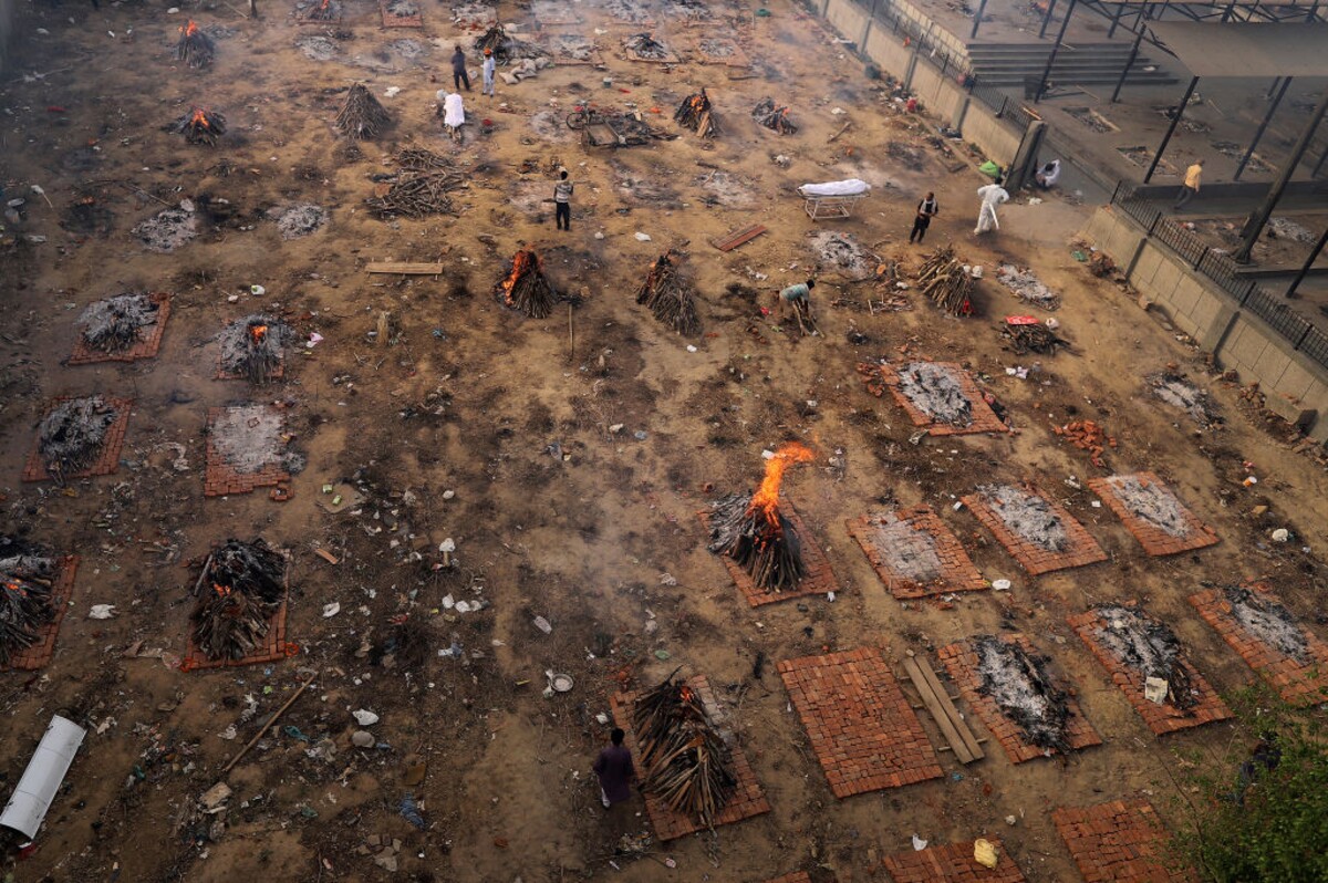 Zahalené telá uprostred horiacich pohrebných hraníc v mieste masových kremácií sú hneď vedľa plného krematória v indickom Naí Dillí.