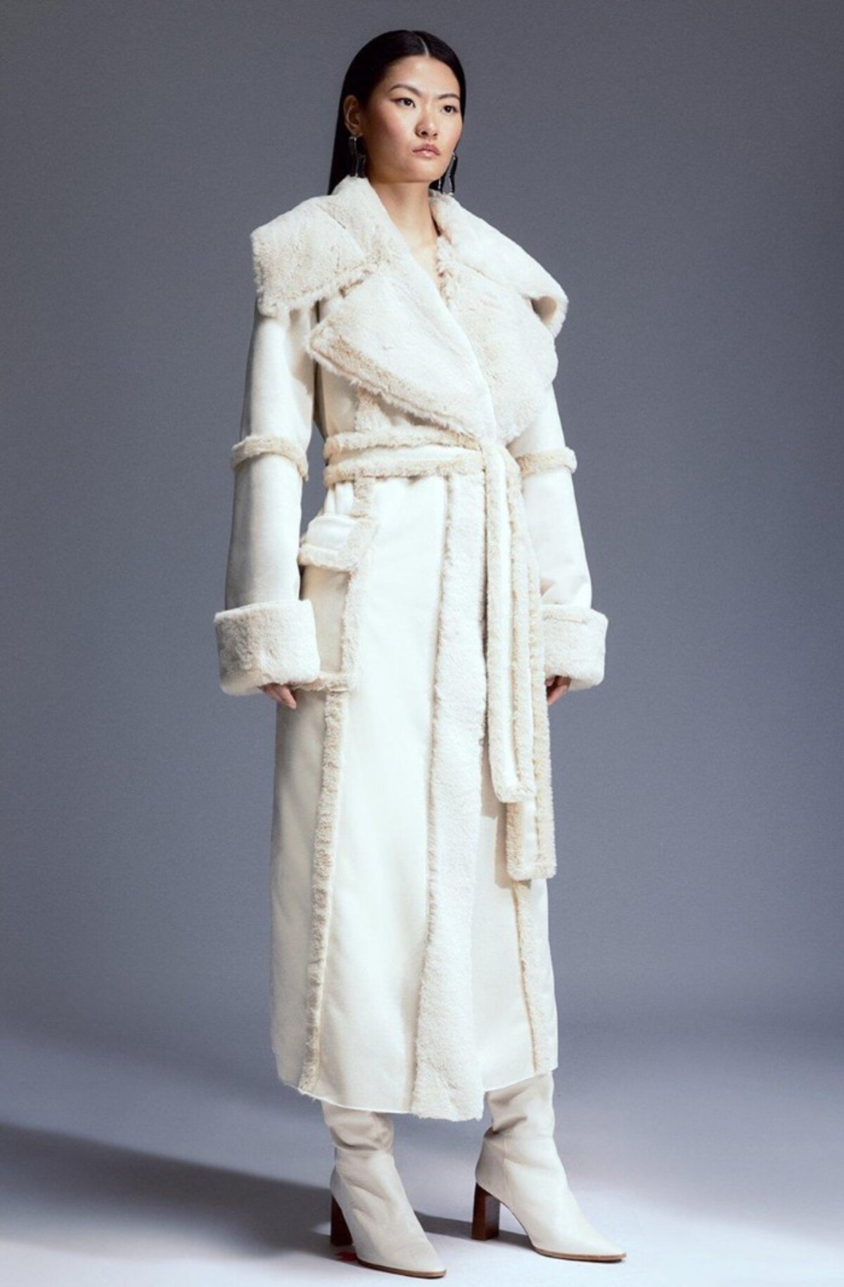 Maxi kabát v bielej farbe od Karen Millen upúta najmä výrazným lemom v oblasti dekoltu a rukávov. Neprehliadnuteľným prvkom je aj ladiaci opasok z nepravej kožušiny. Konkrétny kúsok na fotke kúpiš za 228 eur.
