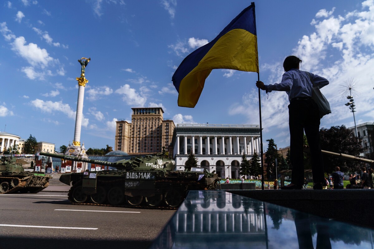 Žena drží ukrajinskú vlajku pred zničenými ruskými tankami vystavenými na Námestí nezávislosti (Majdan) v utorok 23. augusta 2022 v Kyjeve.
