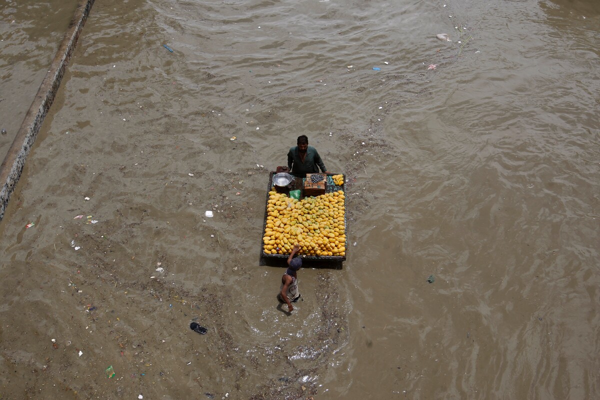 Predavač ovocia sa prechádza po zaplavenej ceste po silných dažďoch v Karáčí v Pakistane v pondelok. Počet obetí súvisiacich s dažďom a záplavami za posledný mesiac stúpol na 147. (11. júla 2022)
