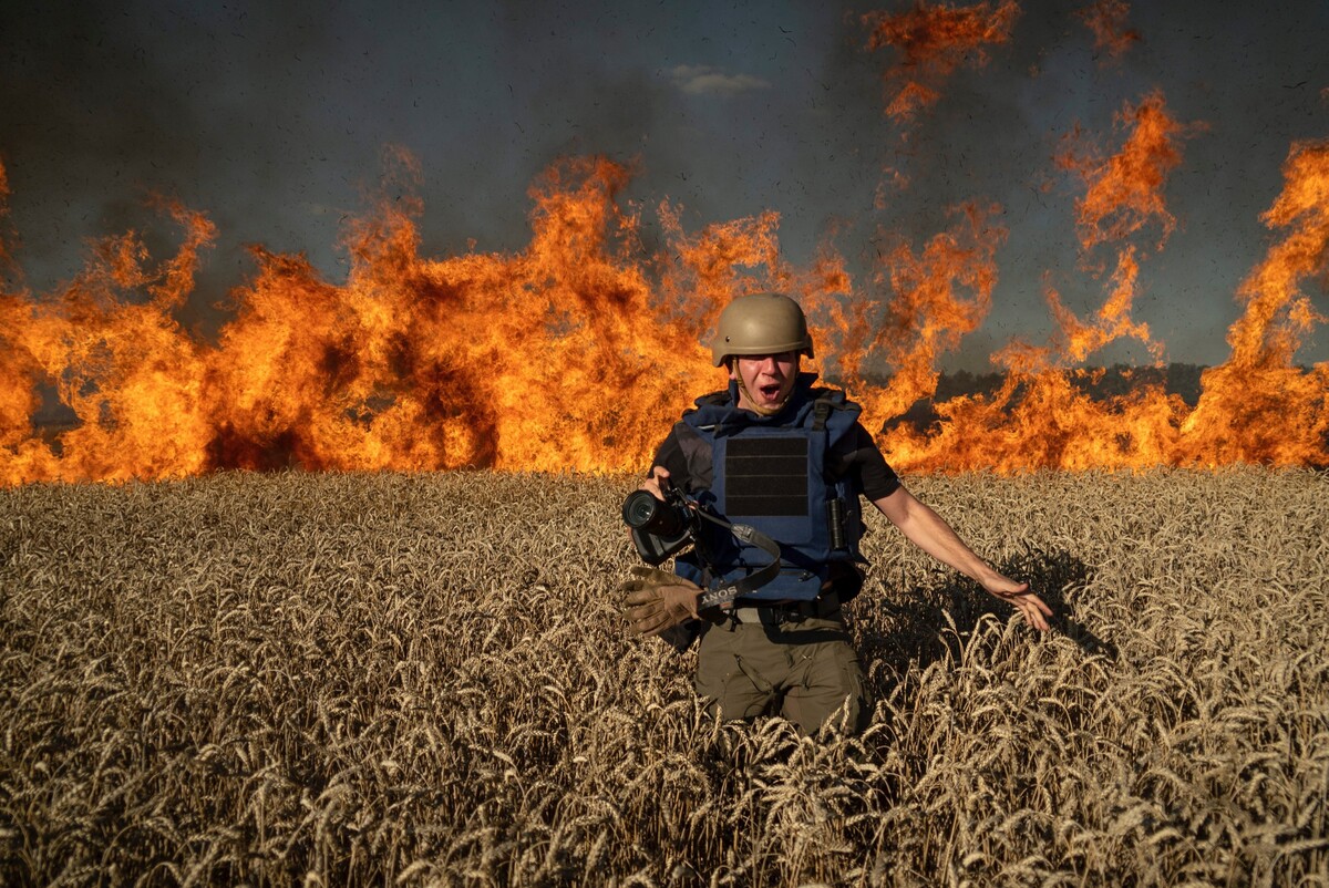 Fotoreportér Jevgenij Maloletka uteká pred požiarom v horiacom pšeničnom poli po ruskom ostreľovaní, len niekoľko kilometrov od ukrajinsko-ruských hraníc v Charkovskej oblasti na Ukrajine. (29. júla 2022)