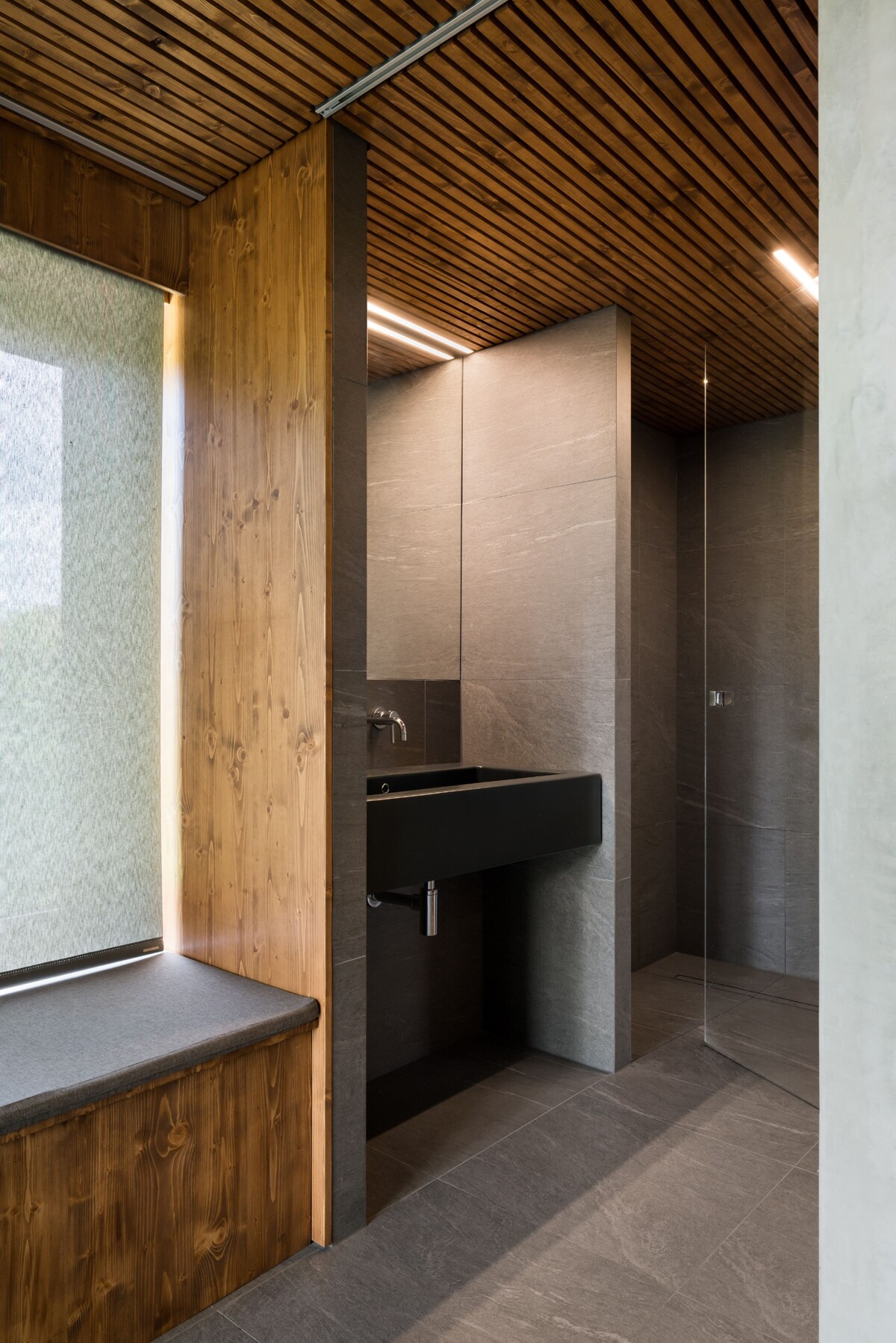 Interiér záhradnej sauny definuje teplé drevo, betónové steny a tmavá dlažba. 