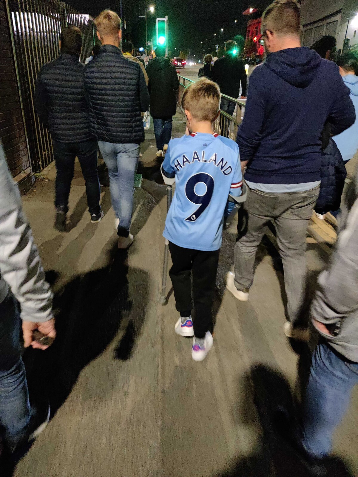 Malý chlapec s barlami v drese hrdinu večera Erlinga Haalanda kráča domov po skončení zápasu.