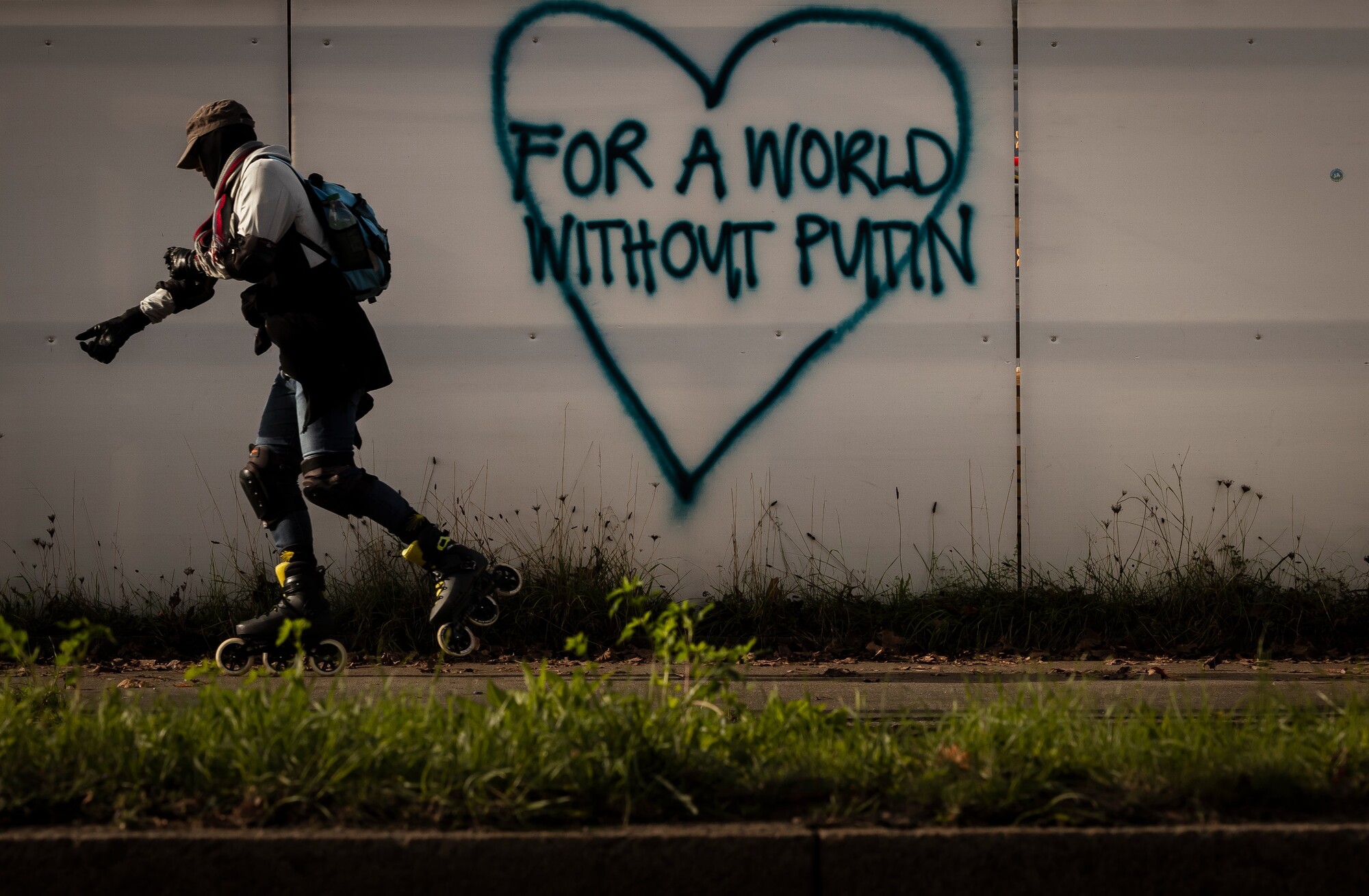 Korčuliar prechádza okolo grafitu na stene s nápisom Za svet bez Putina v Zürichu. (29. októbra 2022)