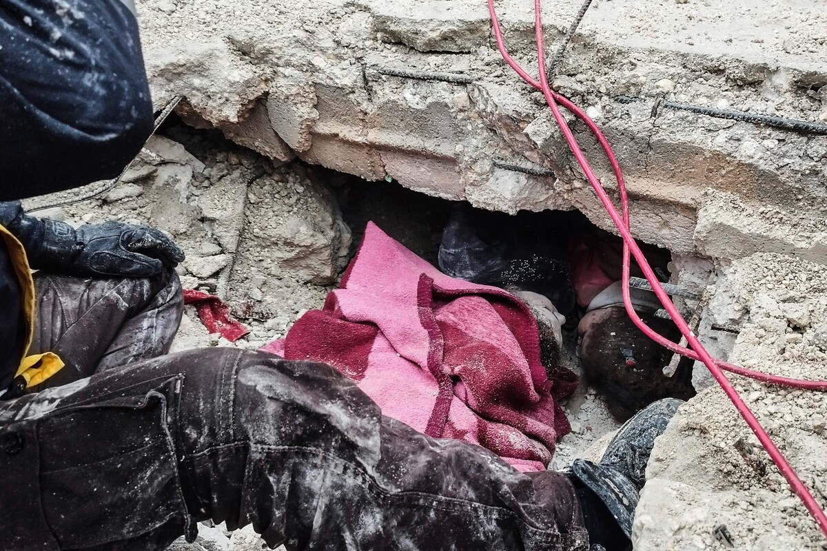 Příslušníci syrské civilní obrany prohledávají trosky budovy, která se zřítila v syrském městě Afrín. Snímek je z pondělí 6. února 2023. 